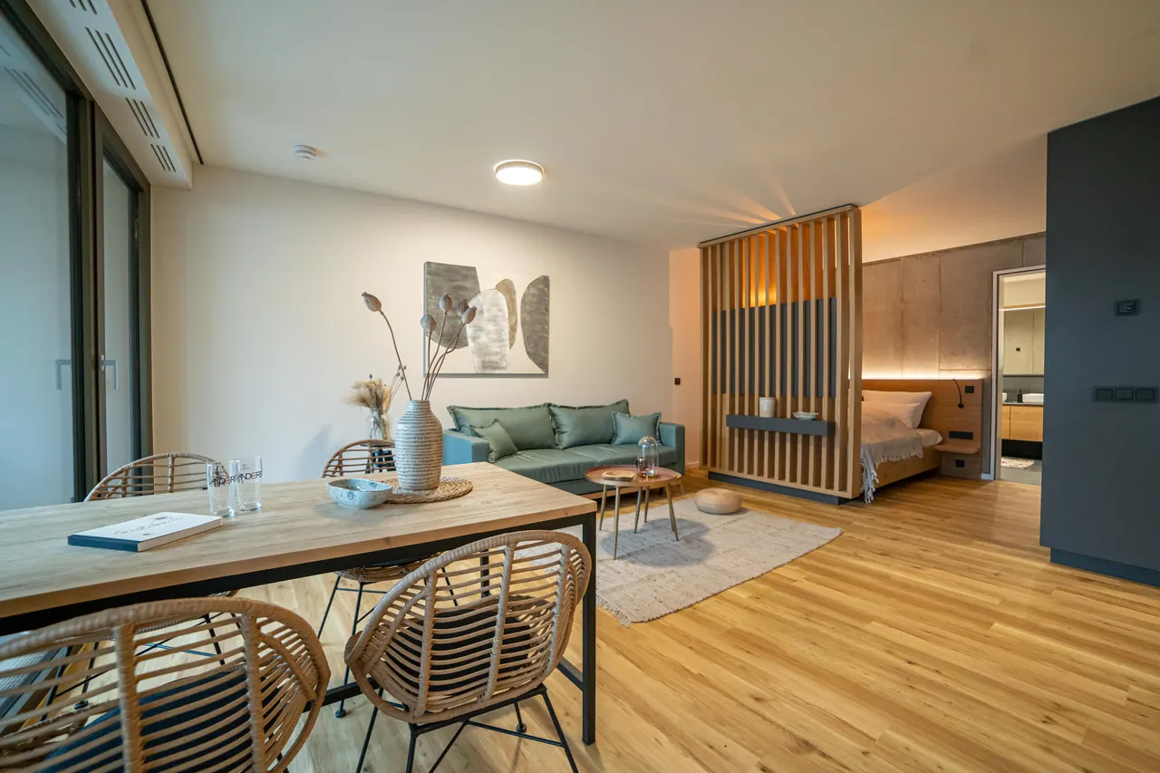 Living room with dining table, sofa and wooden room divider